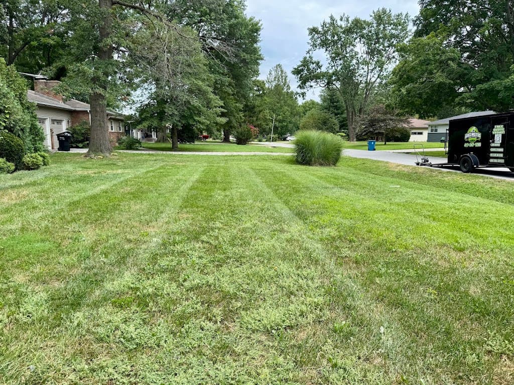Grass Masters branded trailer parked curbside next to a freshly mowed lawn